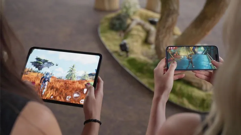 Two players holding an iPad and an iPhone running No Man's Sky